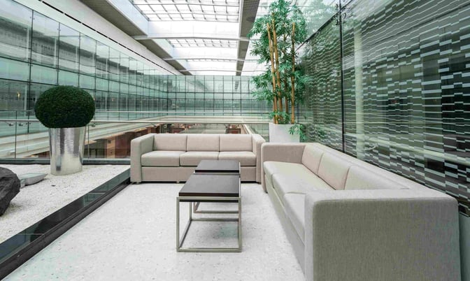 Seating area in Ahlan Lounge at Dubai International Airport features comfortable sofas and tables with views of the terminal.