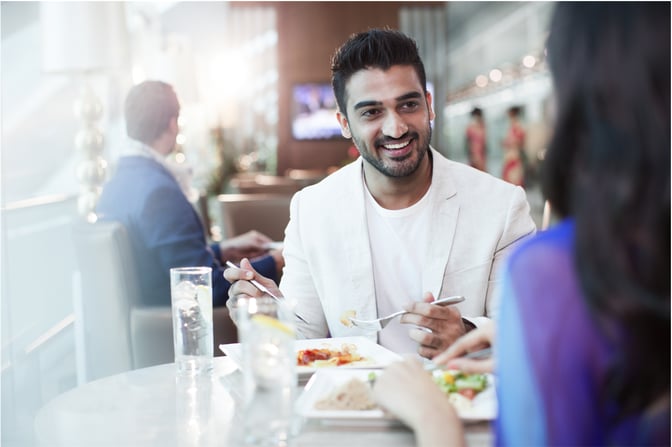Guests enjoy a meal at a dining table in the marhaba Lounge at Dubai International Airport Terminal 3 Concourse A, with visible seating and table service.