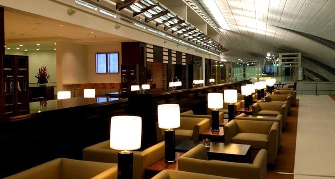 The seating area in marhaba Lounge at Dubai International Airport Concourse B features individual armchairs with tables and lamps, offering a comfortable waiting space.