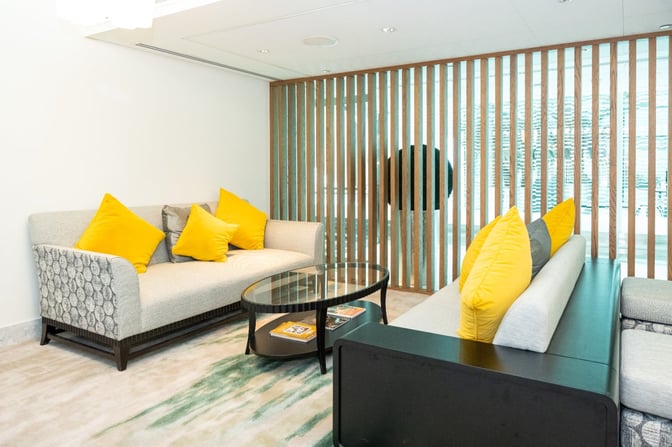 The seating area at Ahlan Lounge, Gate C13, Dubai International Airport, features comfortable sofas and a glass coffee table.