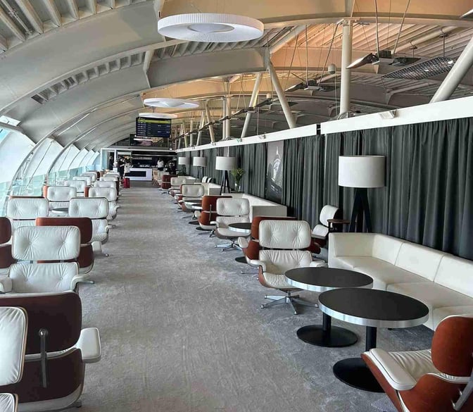 The Adriatic Lounge at Dubrovnik Airport features rows of seating with tables, offering views of the airport through large windows.