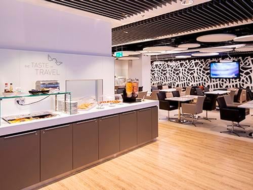 The Open Sky Lounge at Dusseldorf Airport features a self-serve food station with seating areas for dining and relaxation.