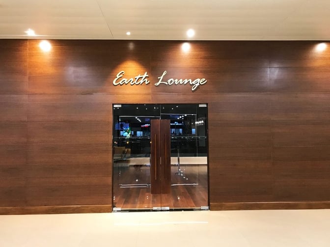 The entrance to the Earth Lounge at Cochin International Airport features glass doors and is located in the departure area.