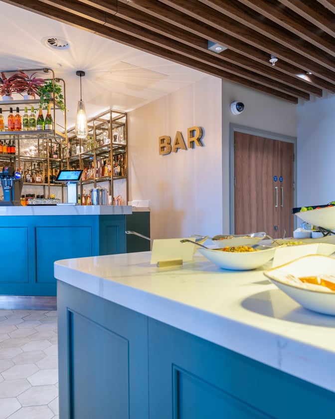 The Aspire Lounge at Edinburgh Airport features a bar with a variety of spirits and a self-serve food area.