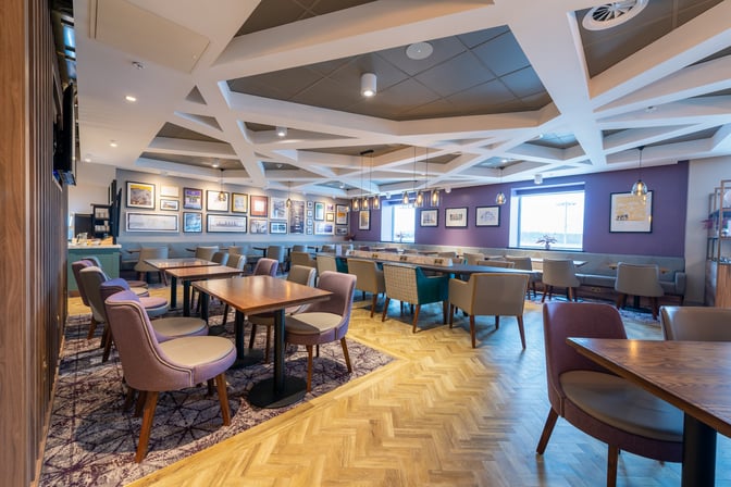 The Aspire Lounge at Edinburgh Airport features a spacious seating area with tables and chairs, offering views of the tarmac.