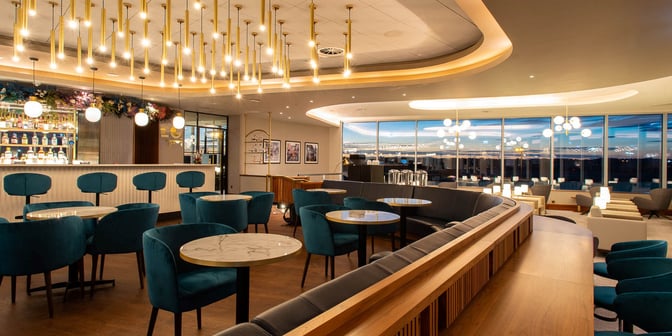 The Plaza Premium Lounge at Edinburgh Airport features a bar area with seating and a view of the airport through large windows.