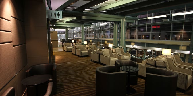 The seating area in the Plaza Premium Lounge at Edmonton International Airport features armchairs and small tables with airport views.