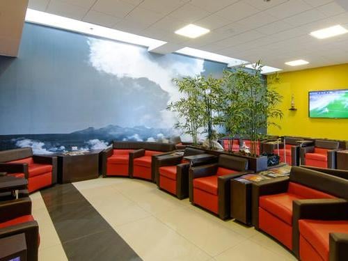 The seating area in the Salones VIP Pacific Club at El Loa Airport features armchairs and a large mural with a mountain scene.