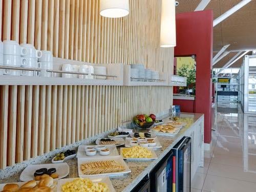 Self-serve breakfast area at Salones VIP Pacific Club in El Loa Airport offers a variety of pastries, fruits, and beverages.