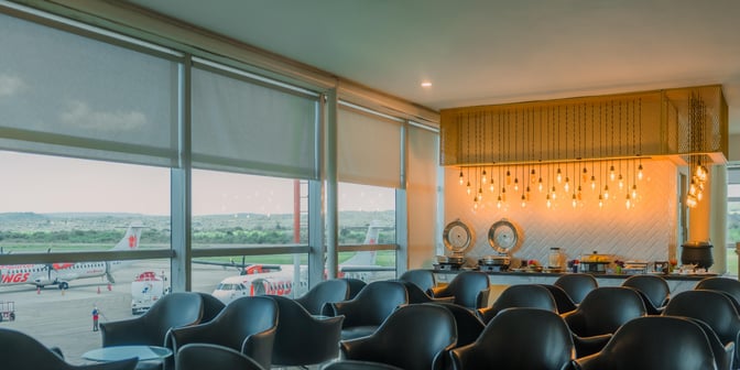 The Concordia Lounge at El Tari Airport features a seating area with views of the runway and a buffet station.