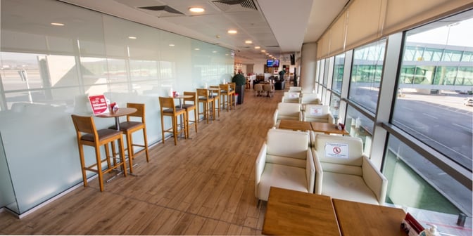 The Primeclass Lounge at Esenboğa International Airport features seating with tables along large windows offering tarmac views.