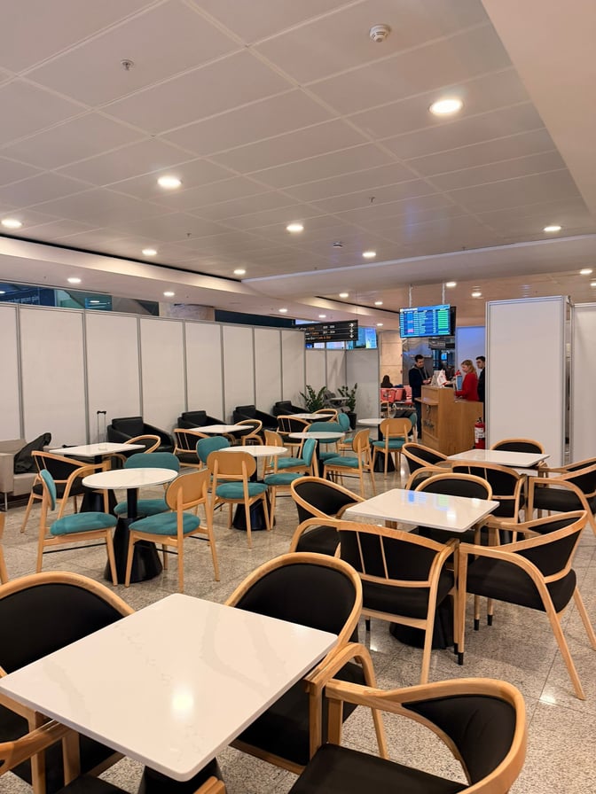 The seating area at Primeclass Pop-Up Lounge in Esenboğa International Airport features tables and chairs for travelers to relax.