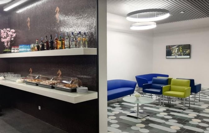 The CIP Lounge at Faro International Airport features a self-serve bar with beverages and snacks, alongside a seating area with armchairs.