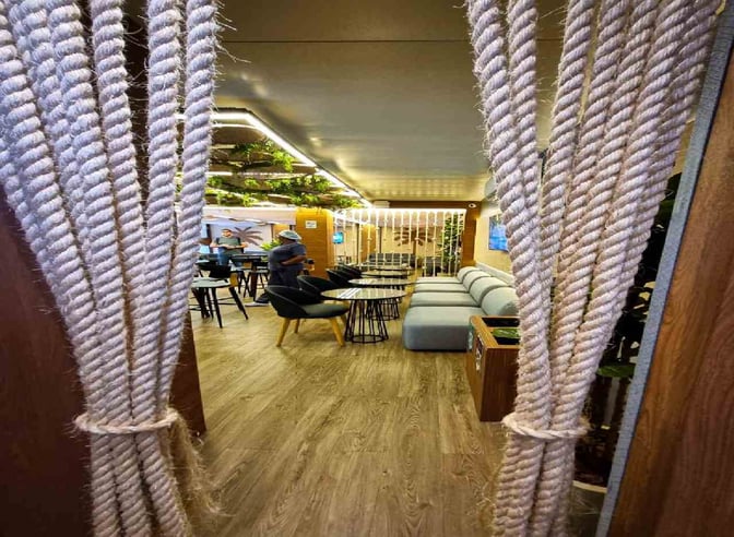 The lounge at Fernando de Noronha Airport features seating areas with sofas and tables, offering a comfortable space for travelers.