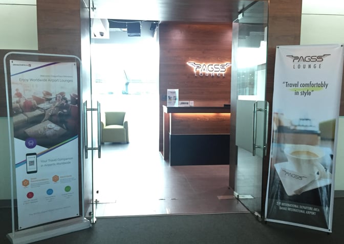 The entrance to the PAGSS Premium Lounge at Francisco Bangoy International Airport features promotional banners and a reception desk.