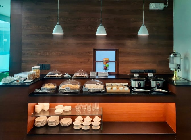 The PAGSS Premium Lounge at Francisco Bangoy International Airport features a self-serve food station with covered dishes and beverage dispensers.