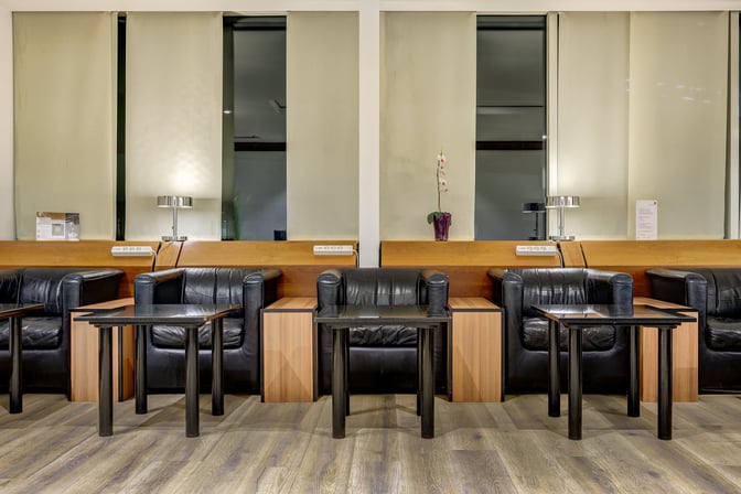 LuxxLounge at Frankfurt Airport features comfortable armchairs with side tables and lamps, providing a relaxing seating area for travelers.