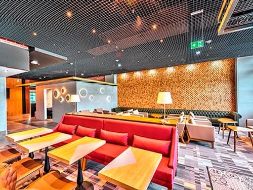 Seating area in Primeclass Lounge at Frankfurt Airport features tables and chairs for dining, with additional couches for relaxation.