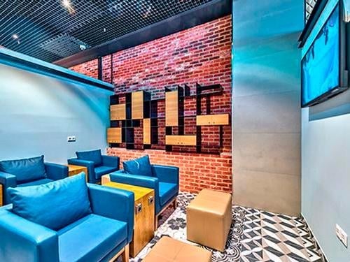 The seating area in Primeclass Lounge at Frankfurt Airport features comfortable chairs and a wall-mounted television for entertainment.