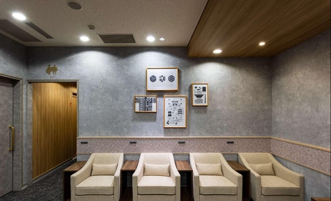 Seating area in the Lounge TIME/International at Fukuoka Airport features comfortable chairs and framed artwork on the wall.