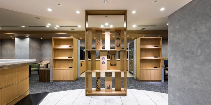 The lounge at Fukuoka Airport features a decorative wooden partition with shelving, providing a semi-private seating area for travelers.