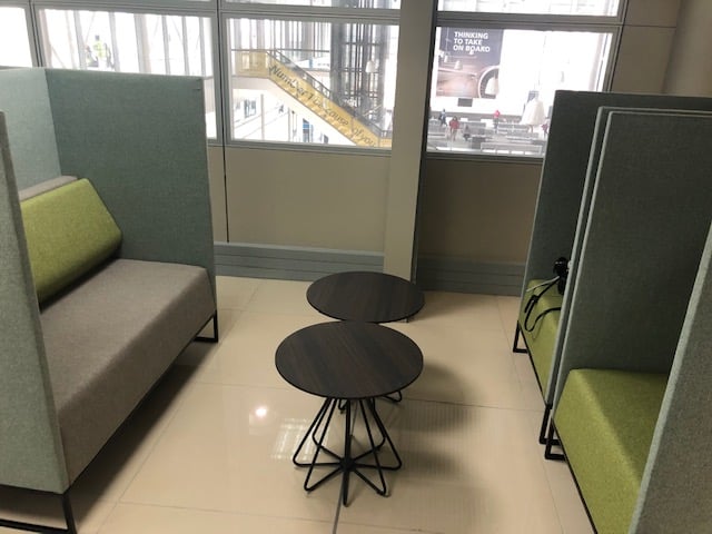 Semi-private seating at Nthula Lounge features cushioned booths and small tables, offering a view of the airport terminal.