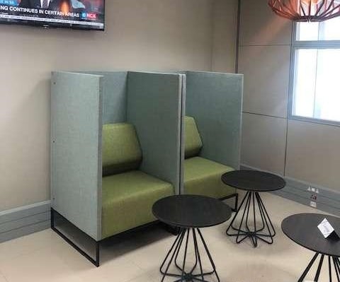 Booth seating at Nthula Lounge in Sir Seretse Khama International Airport offers semi-private spaces with adjacent small tables for travelers.