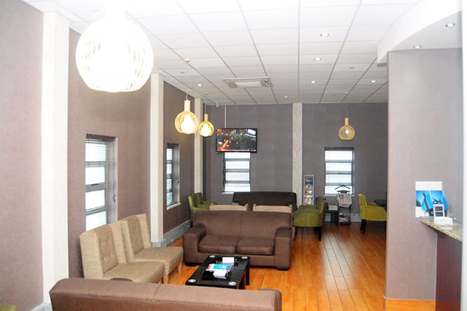 The seating area at Nthula Lounge, Sir Seretse Khama International Airport, features sofas and armchairs with a wall-mounted TV for entertainment.