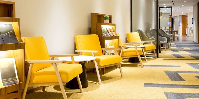 The seating area in Plaza Premium Lounge at Rio de Janeiro Airport features armchairs and magazine racks for passenger comfort and reading.