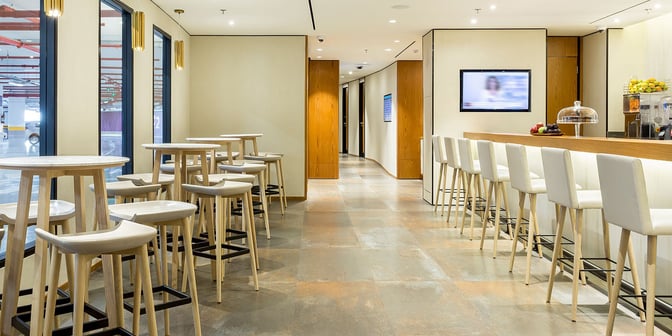 The Plaza Premium Lounge at Rio de Janeiro–Galeão Airport features a bar area with high stools and tables for dining.