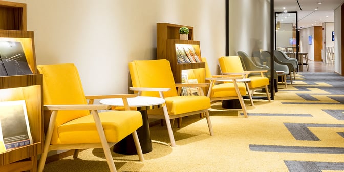 The seating area in Plaza Premium Lounge at Rio de Janeiro Airport features armchairs and magazine racks for passenger comfort and reading.