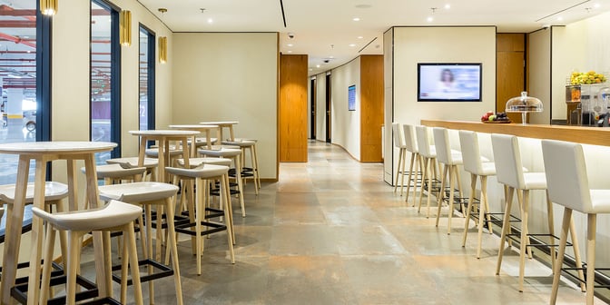 The Plaza Premium Lounge at Rio de Janeiro–Galeão Airport features a bar area with high stools and tables for dining.