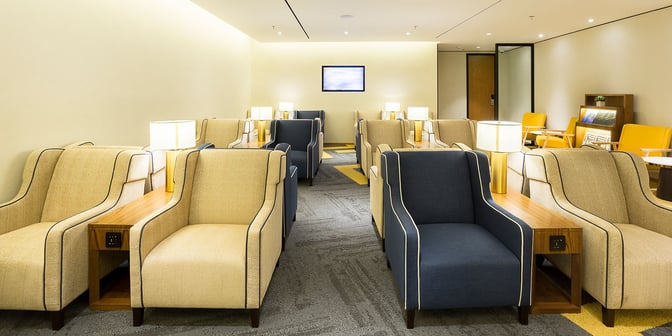 The seating area in Plaza Premium Lounge at Rio de Janeiro Airport features armchairs with side tables and integrated power outlets.