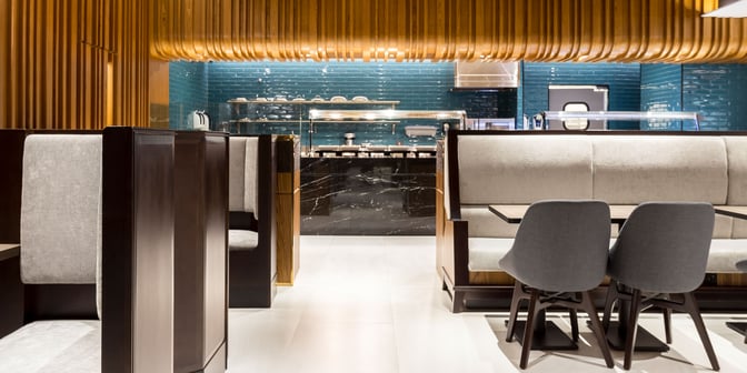 Booth seating in the Plaza Premium Lounge at Rio de Janeiro–Tom Jobim Airport offers semi-private dining with a view of the food area.