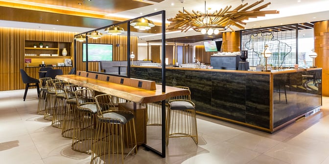 The Plaza Premium Lounge at Rio de Janeiro–Galeão International Airport features a bar area with high-top seating and charging stations.