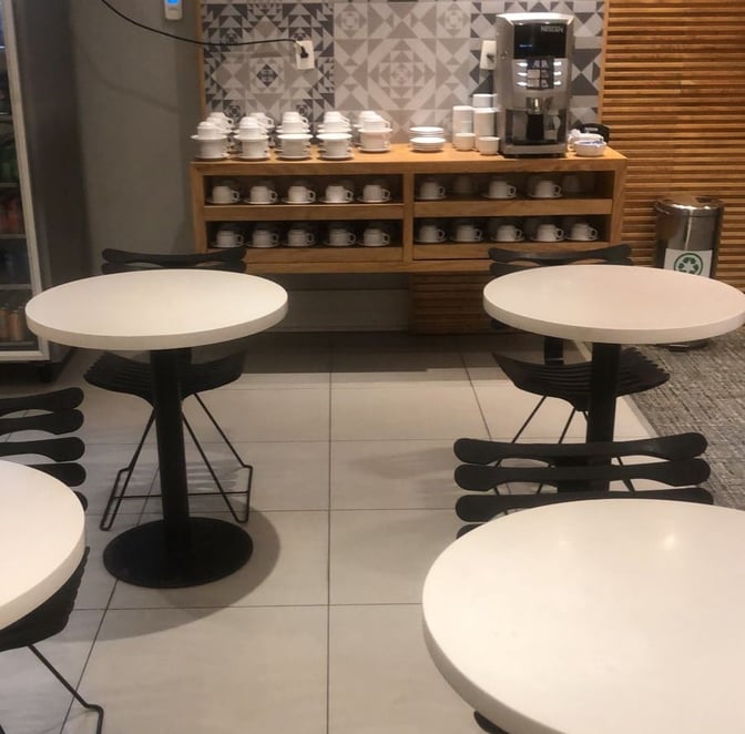 The GOL Premium Lounge at Rio de Janeiro–Galeão International Airport features a coffee station with self-serve cups and tables for seating.