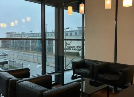 The Executive Lounge at Gdansk Lech Walesa Airport features seating with views of the airport exterior through large windows.