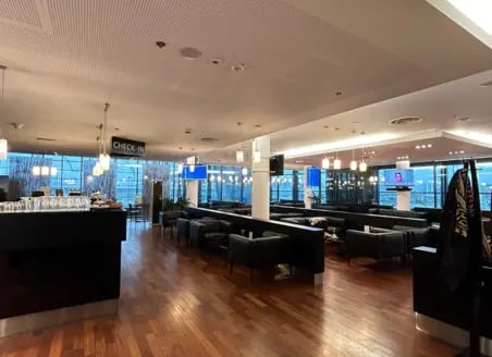 The Executive Lounge at Gdansk Lech Walesa Airport features a spacious seating area with check-in counter and airport views.