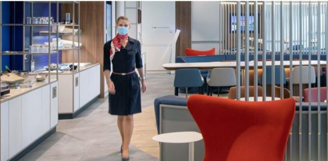 The Air France Lounge at Geneva International Airport features a seating area with tables and chairs, adjacent to a self-serve food station.