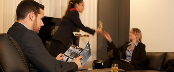 The Swissport Horizon Lounge at Geneva International Airport features comfortable seating with staff serving drinks to guests.