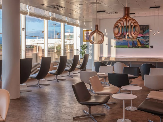 The seating area in the marhaba Lounge at Geneva International Airport features modern chairs and tables with large windows offering airport views.