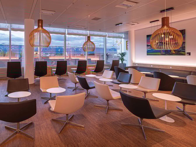 Seating area in the marhaba Lounge at Geneva International Airport features swivel chairs and small tables with views of the tarmac.