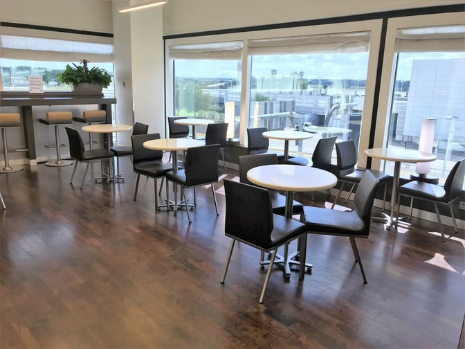 The Air France Lounge at George Bush Intercontinental Airport features a seating area with tables and chairs offering airport views.