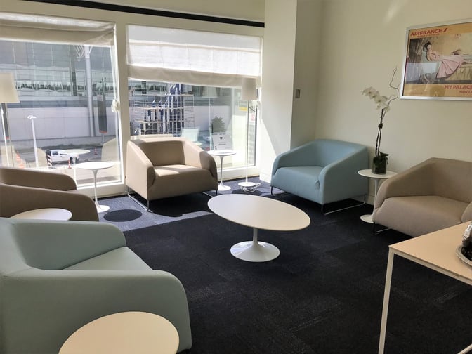 The seating area in the Air France Lounge at George Bush Intercontinental Airport features armchairs and tables with views of the tarmac.