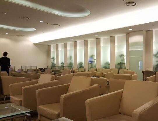 The seating area in Korean Air Lounge at Gimhae International Airport features numerous armchairs and small tables for passenger comfort.
