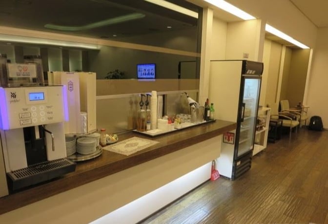 The Korean Air Lounge at Gimhae International Airport features a self-serve beverage station with a coffee machine and refrigerated drinks.