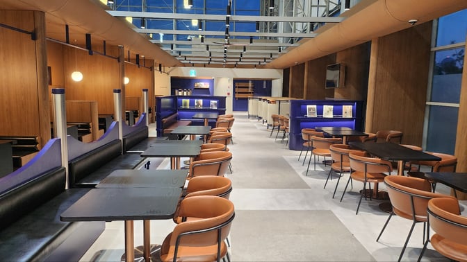 The N Sky Hub Lounge at Gimhae International Airport features a seating area with tables and chairs, offering a comfortable space for travelers.