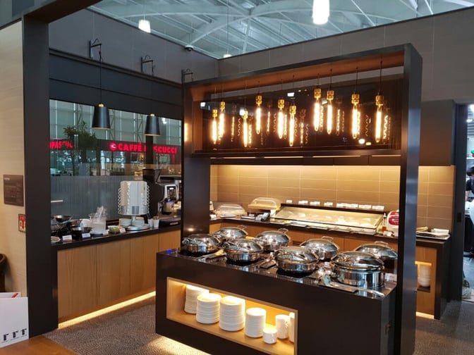 The Sky Hub Lounge at Gimhae International Airport features a self-serve food area with hot dishes and beverage stations.