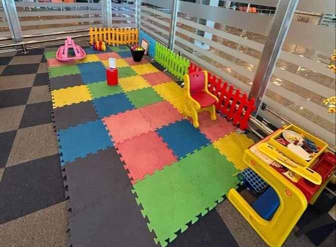 The children's play area at Pearl Lounge, Sphinx International Airport, features colorful foam mats, small chairs, and toys for entertainment.