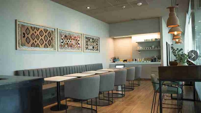 The seating area in JUJUY By AMAE Lounge features booth and table seating with a self-serve beverage station in the corner.